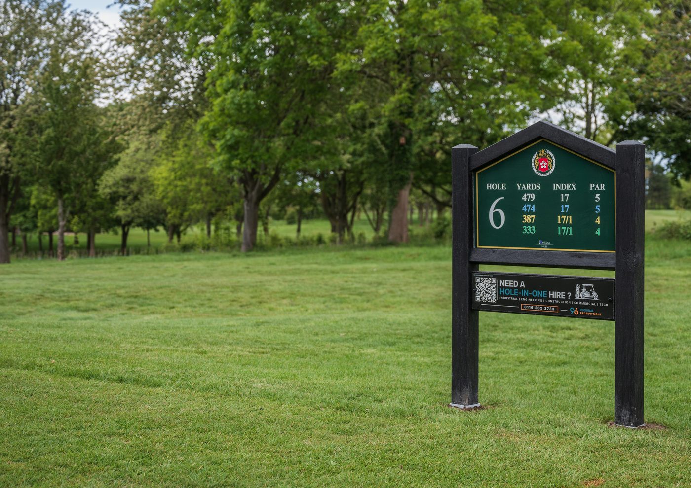 A composite eco wood tee sign standing on the sixth hole, with a sponsor panel beneath the yardage board
