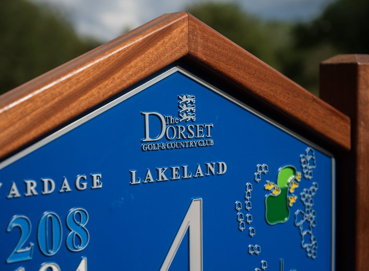 Close-up of a hardwood tee sign at The Dorset Golf & Country Club, showing the timber frame and routed lettering
